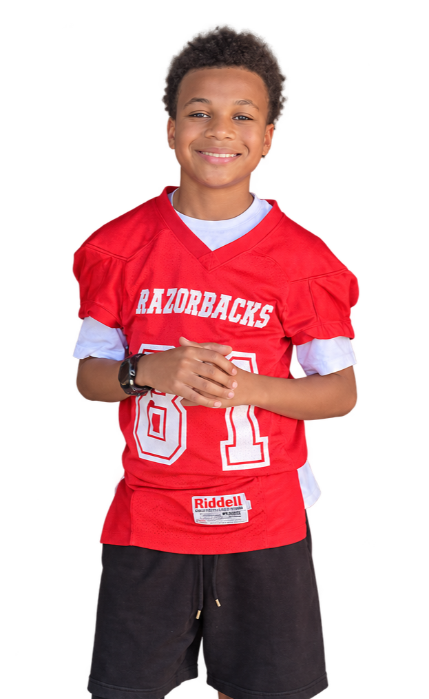 A smiling boy wearing a red football jersey