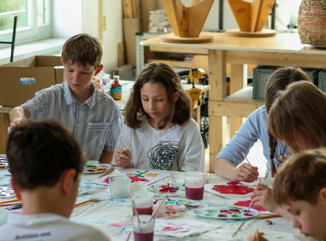 Children painting together with watercolors at a classroom table.